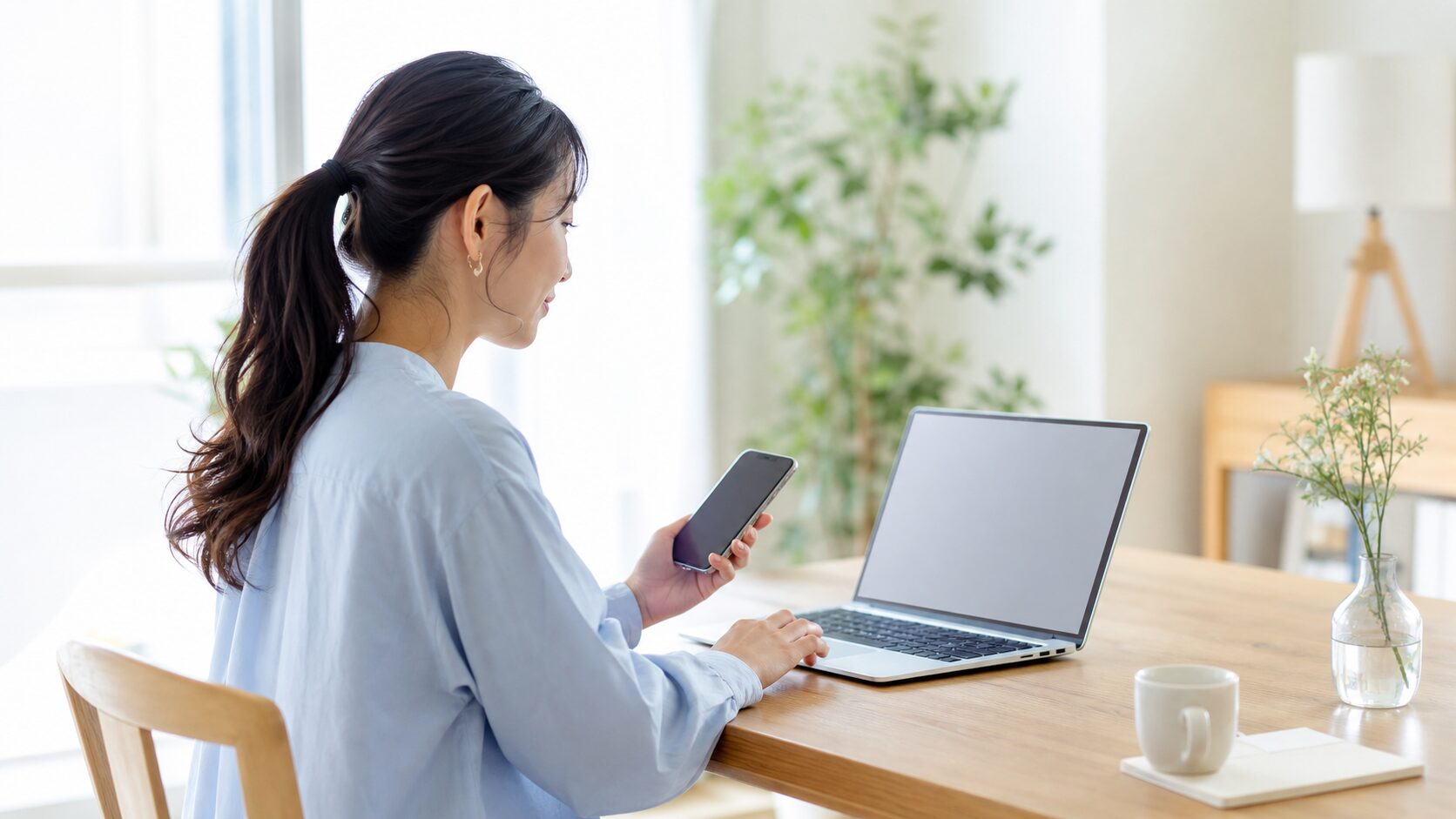 ノートパソコンとスマホで求人情報を見比べる看護師の様子