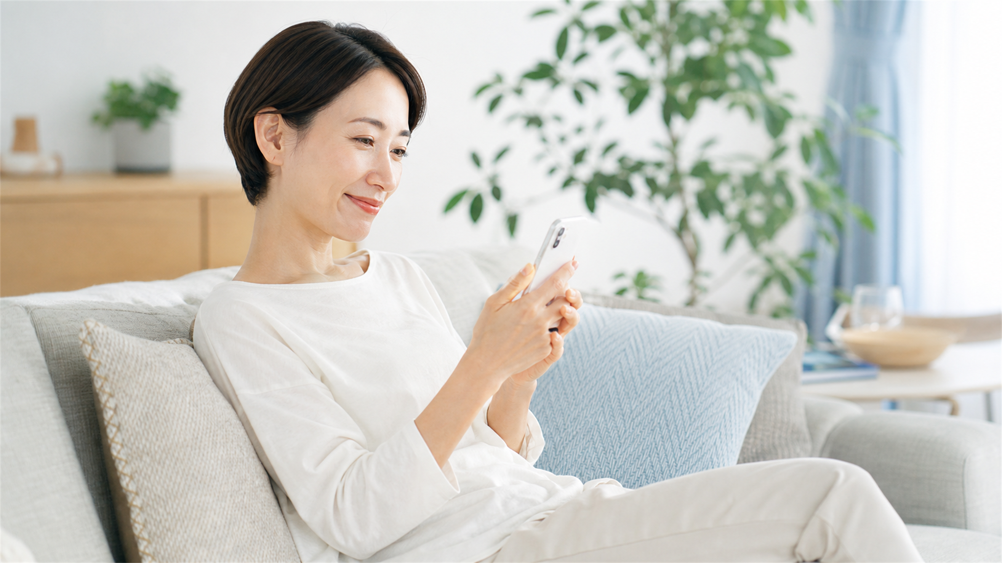 ソファでくつろぎながらスマホで出会いを探す看護師